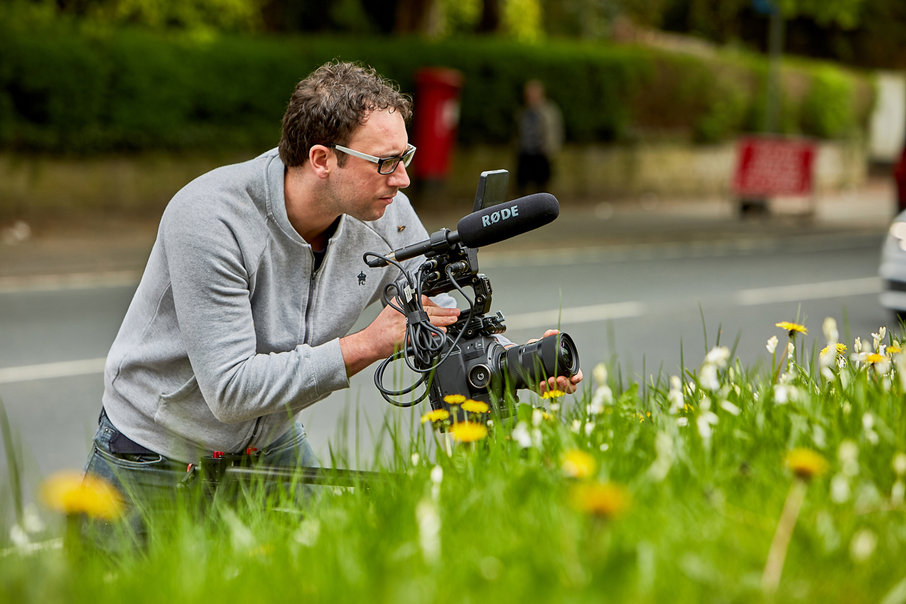 Photo of cameraman filming next to the road