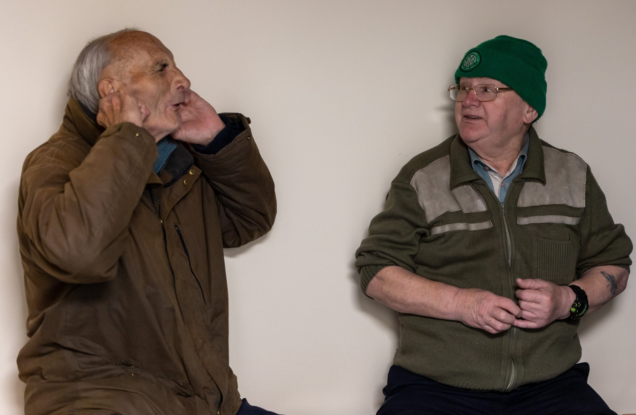 older man covering his ears and another man watch